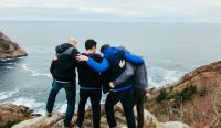 Four missionary students near the ocean praying